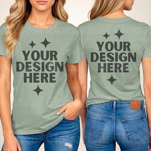 以下が含まれることがあります： 2人の女性がセージグリーンのTシャツを着ています。Tシャツの前と後ろには「YOUR DESIGN HERE」という文字が印刷されています。Tシャツはゆったりとしたフィット感で、クルーネックです。女性は青いジーンズを履いています。