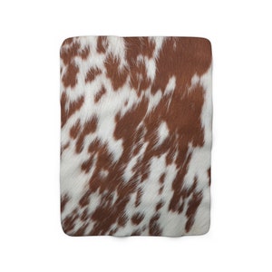 May include: Brown and white cowhide patterned fabric with a soft, fuzzy texture.