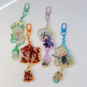 Può includere: Cinque portachiavi in acrilico colorati con disegni di personaggi dei cartoni animati. Ogni portachiavi presenta un personaggio diverso con una chiusura colorata abbinata. I personaggi includono una varietà di animali e persone. I portachiavi sono appesi su uno sfondo bianco.