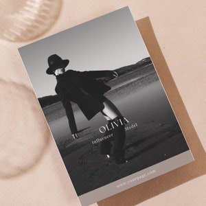 May include: Black and white photo of a person wearing a hat and coat standing on a beach. The text "Olivia Influencer Model" and "www.yourpage.com" are on the bottom of the image.