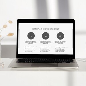 May include: A laptop computer screen displays a professional career path with three numbered steps. Each step includes a company name, job title, and a list of responsibilities. The laptop is on a white desk with a glass of water and dried flowers in a glass vase.