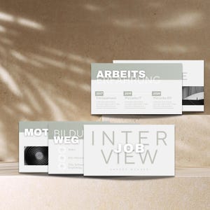 May include: A set of light grey and white business cards with text. The cards display the words "INTERVIEW JOB VIEW" and "ARBEITSERFAHRUNG". Other cards show the words "MOT BILDU WEG". The cards are arranged on a light brown surface.