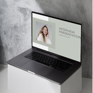 May include: A laptop computer displaying a presentation titled "Interview Präsentation" with the name Andrea Schiller. The presentation features a photo of a woman with curly hair smiling.