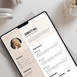 May include: A digital resume template on a tablet, featuring a photo of a person, contact information, and sections for experience, education, and languages. The design uses a neutral color palette with black text.