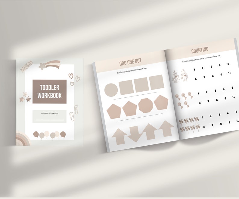 May include: A toddler workbook with a brown cover and the text "Toddler Workbook" in white. The cover also features a star, a shooting star, hearts, and a rainbow. The inside pages show activities for counting and odd one out.