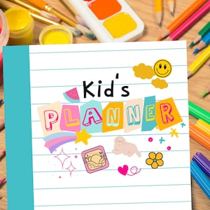 Op de afbeelding: Een blauwe en witte planner met de tekst "Kid's Planner" in kleurrijke letters. De planner is omringd door kleurrijke knutselmaterialen, waaronder verf, stiften en potloden.