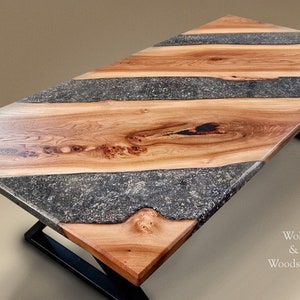 May include: A wooden table top with a black epoxy resin inlay. The table top has a natural wood grain pattern and is finished with a clear coat. The table top is supported by a black metal base.