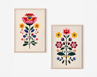 Può includere: Due stampe artistiche floreali incorniciate. Le stampe presentano fiori stilizzati in rosso, rosa, giallo e blu su sfondo crema. Le cornici sono di colore legno chiaro. L'arte è in stile arte popolare.