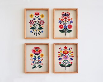 Può includere: Quattro stampe artistiche floreali incorniciate. Ogni stampa presenta un colorato design floreale stilizzato con fiori rossi, rosa, gialli e blu su sfondo crema. Le cornici sono in legno chiaro e l'arte è esposta su una parete bianca.