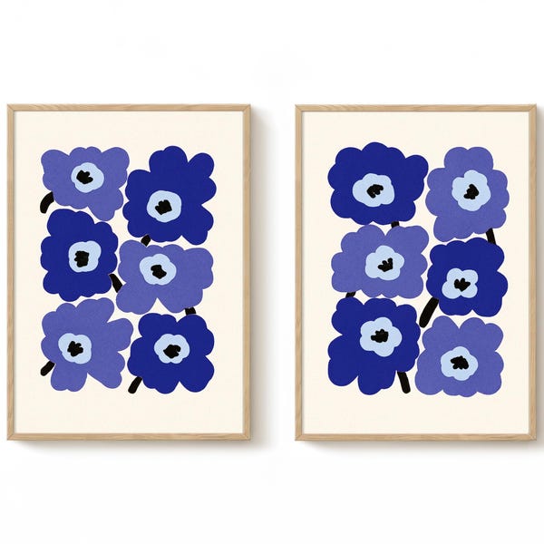 Può includere: Due stampe artistiche incorniciate con disegni floreali blu stilizzati. Ogni stampa presenta una griglia di sei fiori in varie tonalità di blu, con steli neri e centri bianchi, su uno sfondo color crema.