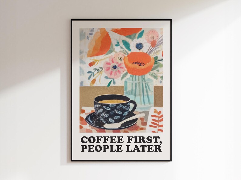 May include: Framed art print featuring a coffee cup on a saucer with a spoon, set against a floral background. The print includes the text "COFFEE FIRST, PEOPLE LATER" in bold, black letters.