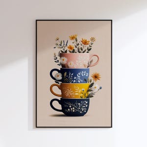 May include: A framed print featuring a stack of four decorative teacups, each a different color: pink, blue, yellow, and navy. Each cup is adorned with floral designs and filled with flowers. The background is a neutral beige.