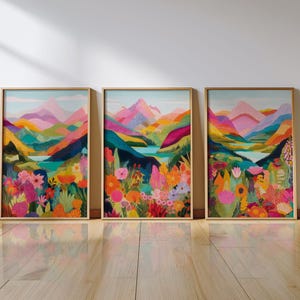 May include: Three framed art prints depicting colourful mountain scenery and bright floral displays. The artwork uses pinks, oranges, blues, and greens, creating a lively artistic display. The frames are a warm gold colour.
