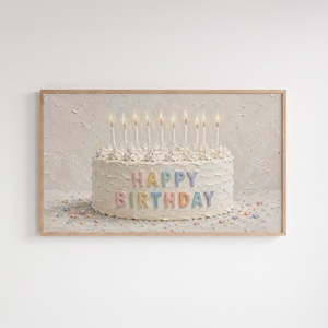 Könnte beinhalten: Ein gerahmter Kunstdruck, der eine runde, weiß glasierte Torte mit strukturierter Creme zeigt. Die Torte ist mit zehn brennenden Kerzen verziert und trägt den pastellfarbenen Schriftzug HAPPY BIRTHDAY auf der Vorderseite. Bunte Streusel liegen davor.