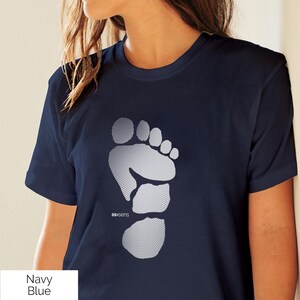 Puede incluir: Camiseta azul marino con un gráfico de pie punteado blanco y el texto "05:sens". La camiseta es de color liso y tiene mangas cortas. El texto "Navy Blue" es visible en la esquina inferior izquierda.