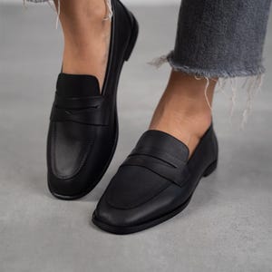 May include: A pair of black leather loafers with a simple design. The loafers have a rounded toe and a low heel.