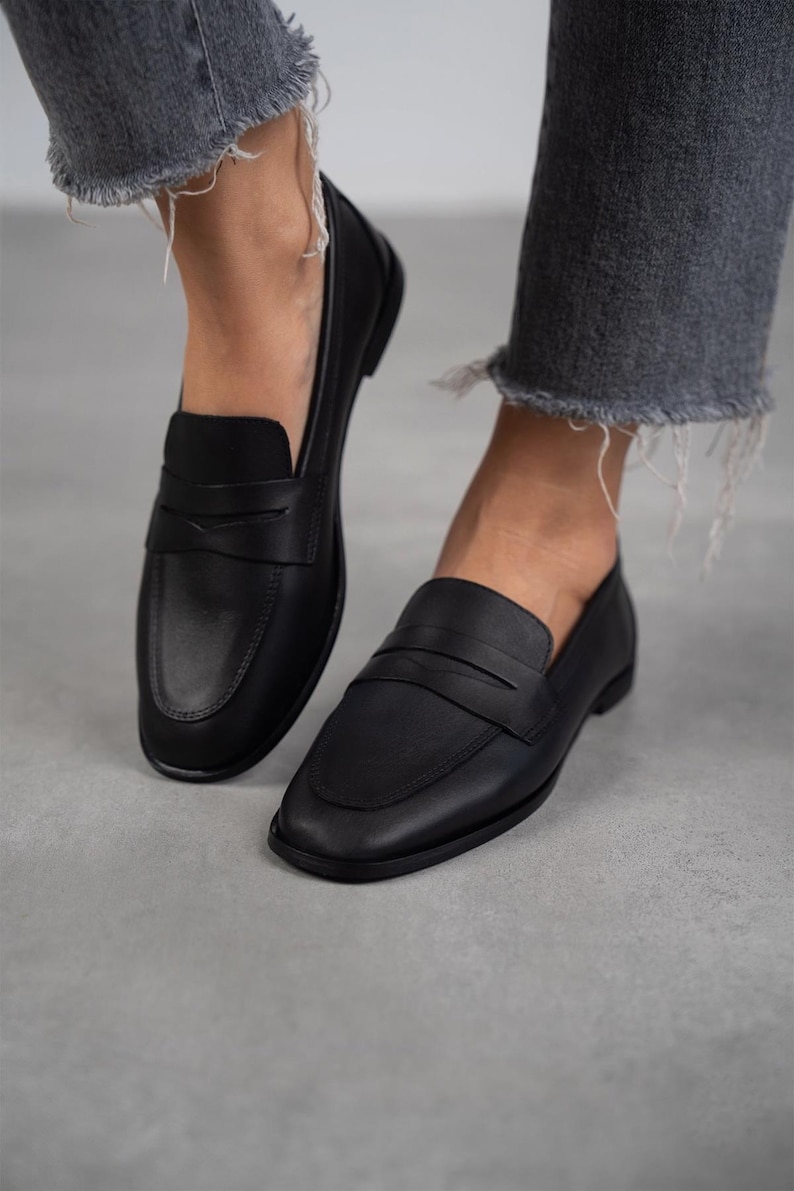 May include: A pair of black leather loafers with a simple design. The loafers have a rounded toe and a low heel.