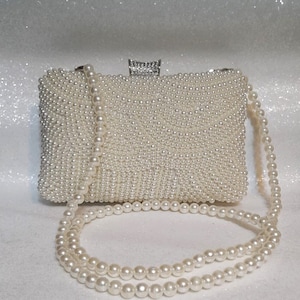 Elegante bolso de mano color marfil con perla y herrajes plateados: perfecto para novias o damas de honor.