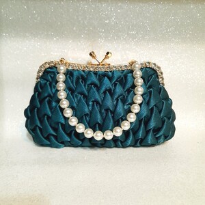 Elegante bolso de mano verde esmeralda con asa de perla y herrajes dorados brillantes