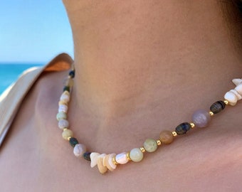 May include: A multi-colored beaded necklace with a variety of natural stones and shell accents. The necklace features a mix of green, brown, white, and purple beads.