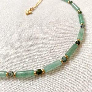 Pode incluir: Um colar de contas verdes e douradas com um pequeno fecho dourado. O colar &eacute; feito com contas de pedra verde e espa&ccedil;adores dourados.