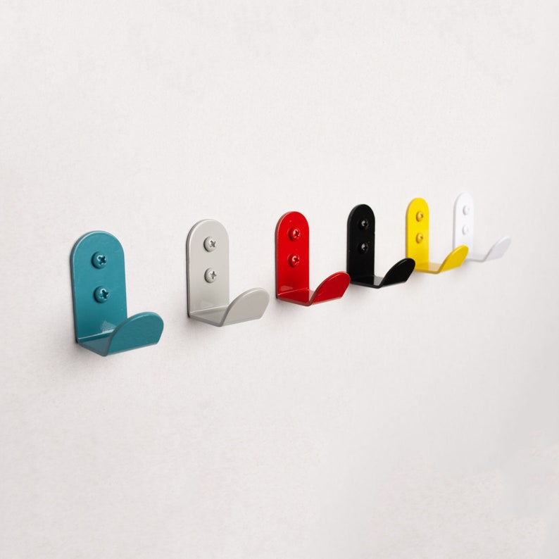 Puede incluir: Conjunto de seis ganchos de pared en varios colores, incluyendo azul verdoso, rojo, negro, amarillo y blanco. Cada gancho tiene una forma redondeada y un dise&ntilde;o simple.