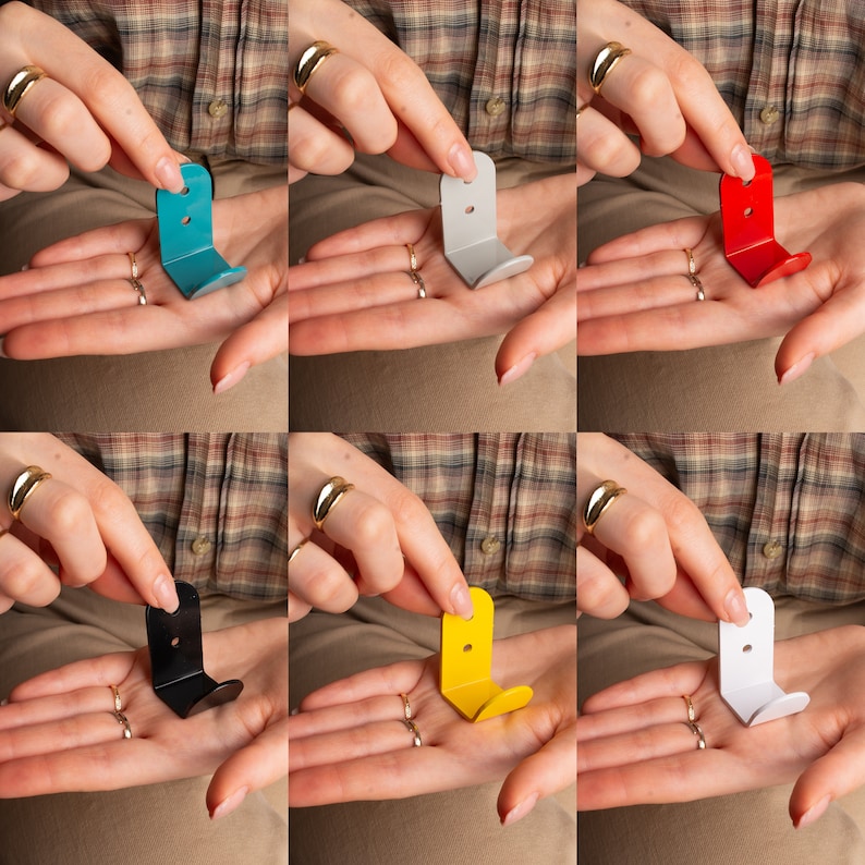 Puede incluir: Seis ganchos de metal de diferentes colores para colgar objetos en una pared. Los ganchos son de varios colores, incluyendo azul, gris, rojo, negro, amarillo y blanco.
