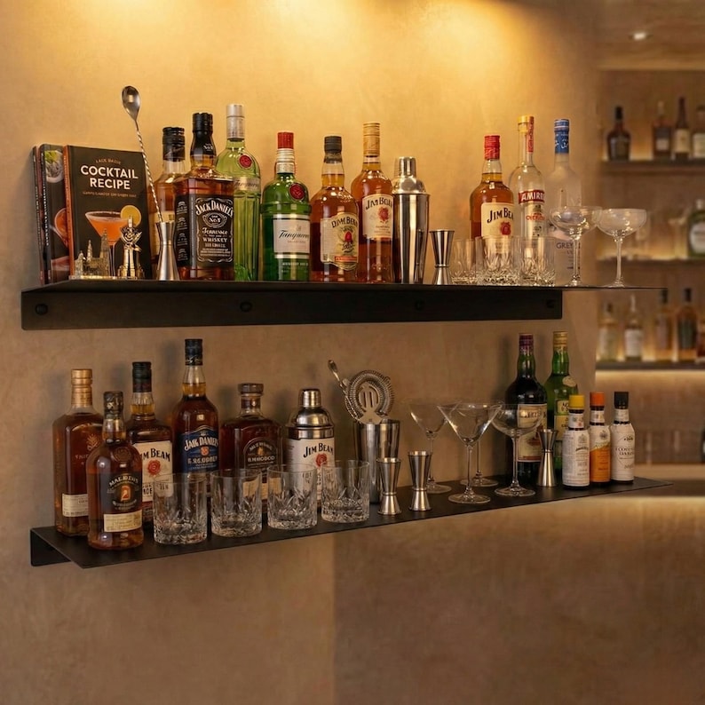 May include: A home bar setup with two black shelves displaying various liquor bottles, cocktail mixers, shakers, and glassware. A cocktail recipe book and bar tools are also visible, suggesting a focus on mixology.