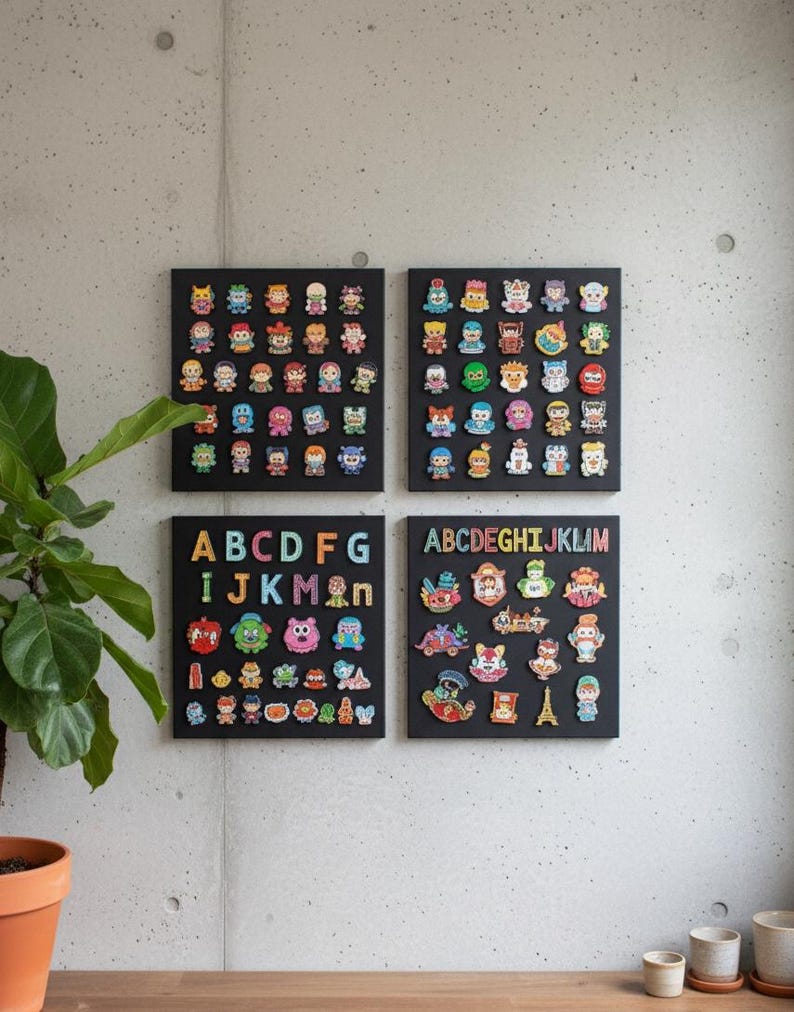 May include: Four black square art pieces are mounted on a gray concrete wall. Each piece features colorful, cartoon-like characters. Two pieces display the alphabet, while the others showcase a variety of figures. A potted plant is visible on the left.