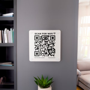 Op de afbeelding: Een wit bord met een zwarte QR-code en de tekst "SCAN FOR WIFI" met een wifi-symbool. Onder de QR-code staat "NETWORK NAME" en "PASSWORD".