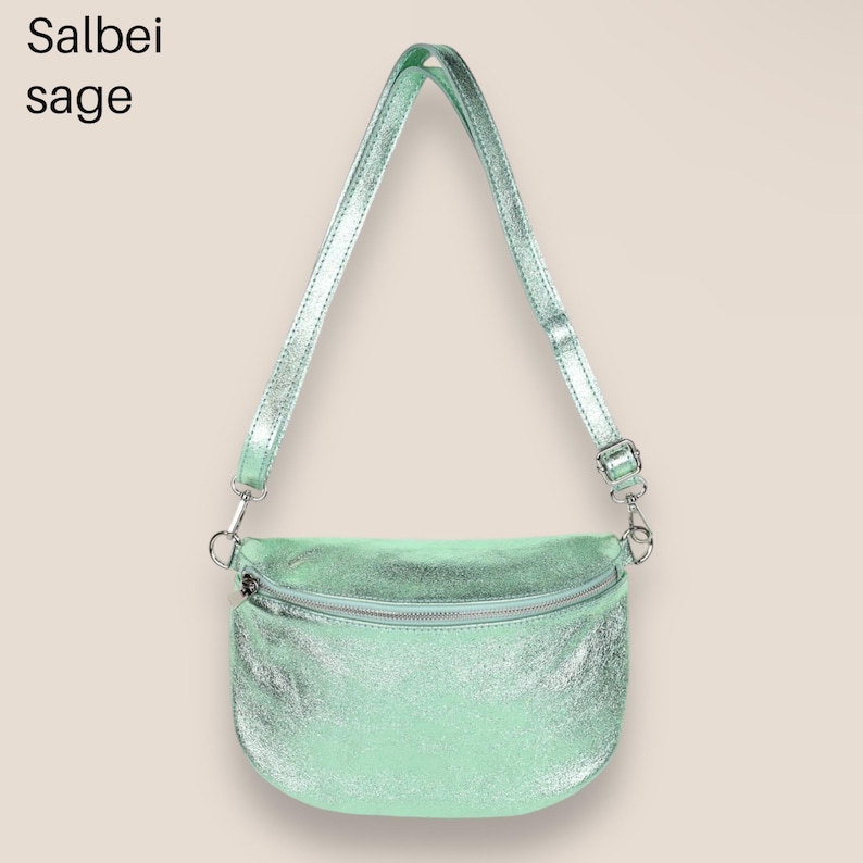May include: A light green metallic crossbody bag with a silver zipper and adjustable strap. The bag has a slightly curved shape and a textured finish.