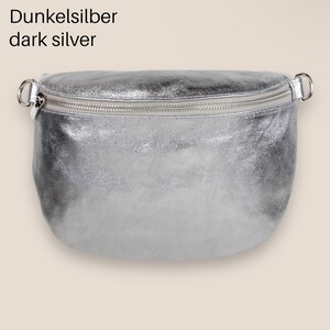 May include: A silver leather fanny pack with a zipper closure. The text "Dunkelsilber dark silver" is above the bag.