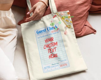 May include: A white canvas tote bag with a blue and red "Guest Check" design. The bag has a grid pattern and the text "Your Custom Text Here" is printed in red. The bag has a blue and white check pattern and the number 561470 is printed on the bag.