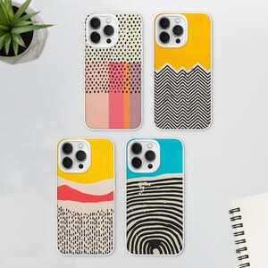 May include: Four different iPhone cases with abstract geometric designs. The cases are white with a clear plastic back and feature different patterns in black, white, yellow, red, pink, blue, and orange.