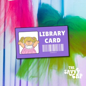 Puede incluir: Una tarjeta de biblioteca morada con una imagen de dibujos animados de una muñeca Cabbage Patch Kid. La tarjeta tiene el texto "LIBRARY CARD" y un código de barras con el número "542881G57".