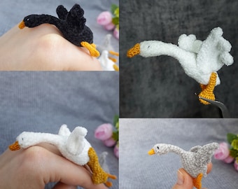 Può includere: Quattro figurine di oca all'uncinetto in diversi colori. Un'oca nera, un'oca bianca, un'oca grigia e un'oca bianca con un becco giallo.