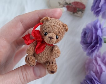 Kleine bruine knuffelbeer met rode strik. Schattige kleine knuffelbeer om te verzamelen. Pop huisdier. Kerstmis, Nieuwjaar, verjaardagscadeau.
