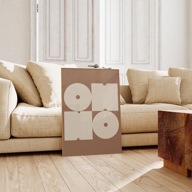 May include: A framed print with a geometric design in shades of brown and white. The print features four overlapping circles and squares, creating a modern and abstract look.