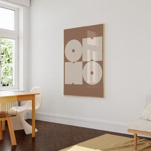 May include: A brown framed print with the word "OH NO" in white letters on a beige background. The letters are made up of geometric shapes.