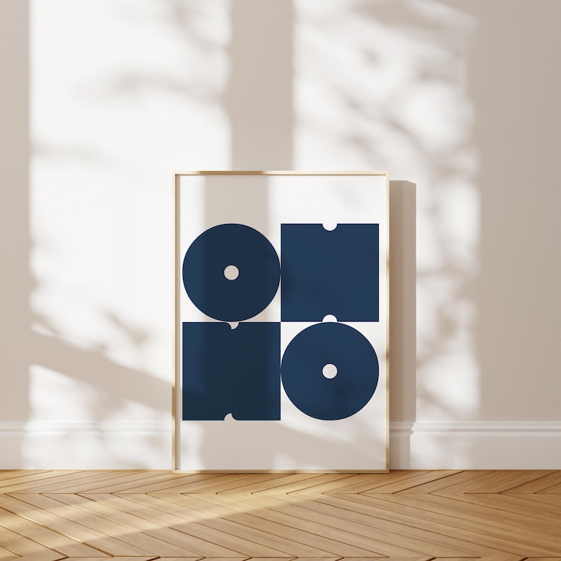 May include: A framed print with a geometric design featuring four navy blue shapes: a circle, a square, and two rectangles. The shapes are arranged in a grid pattern on a white background.