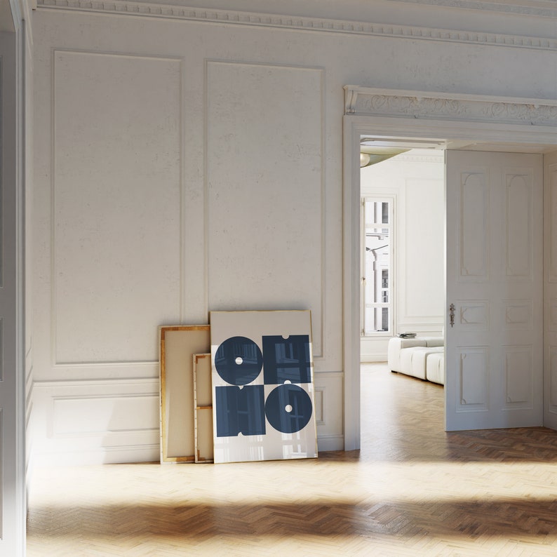 May include: A white room with a large, framed print of the word "OHIO" in blue letters. The print is leaning against a wall, next to a wooden door. The room has white walls and a wooden floor.