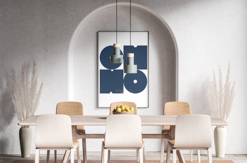 May include: A dining room with a wooden table and six chairs. The table is set with a bowl of lemons. A framed print with a blue geometric design hangs on the wall above the table. Two tall vases with dried pampas grass are on either side of the table.