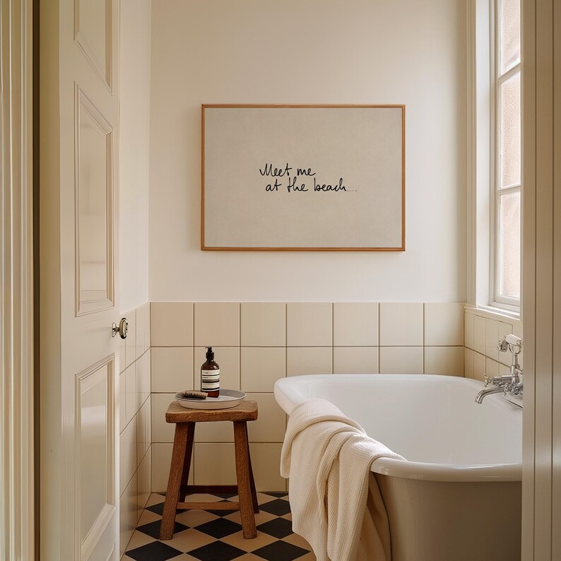 Puede incluir: Interior de ba&ntilde;o con un cuadro enmarcado con el texto "Meet me at the beach". Un taburete de madera sostiene una botella y una bandeja. Tambi&eacute;n se ven una ba&ntilde;era blanca y una ventana. El suelo tiene un patr&oacute;n de cuadros blancos y negros.