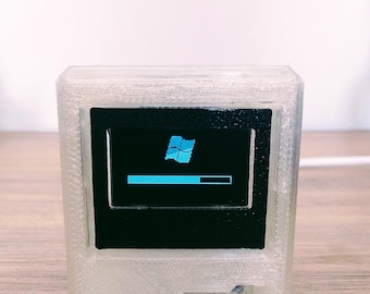 May include: A white plastic 3D printed model of a vintage computer with a black screen displaying the Windows logo and a progress bar.
