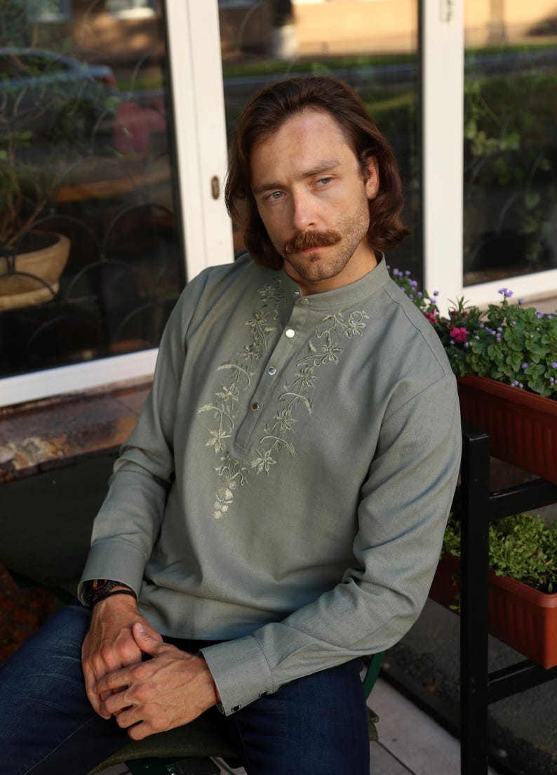 Puede incluir: Camisa de manga larga verde salvia con bordado floral alrededor del cuello y tapeta abotonada. La camisa tiene cuello mandar&iacute;n y se combina con vaqueros azules. La camisa est&aacute; hecha de un material suave y c&oacute;modo.