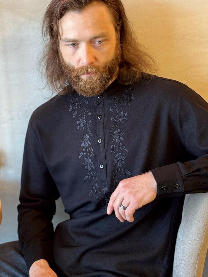 Puede incluir: Camisa negra de manga larga con bordado floral en la parte delantera y en los pu&ntilde;os. La camisa tiene cuello mandar&iacute;n y cierre de botones. Las mangas tienen pu&ntilde;os abotonados. Hecha de un material suave y c&oacute;modo.