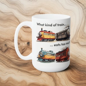 May include: White ceramic coffee mug with a black and white illustration of three cartoon trains. The text "What kind of train... eats too much?" is printed on the mug.