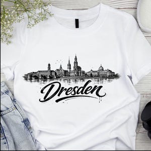 May include: White t-shirt with a black and white illustration of the Dresden skyline. The word "Dresden" is written in a stylish script font below the skyline. The shirt is made of a soft, comfortable material.