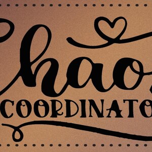 May include: A brown background with black text that reads "Chaos Coordinator" with a heart symbol above the word "Chaos" and below the word "Coordinator".
