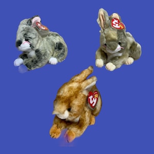 May include: Three plush toy bunnies with Ty tags. One is gray and white, one is brown and white, and one is orange and white.